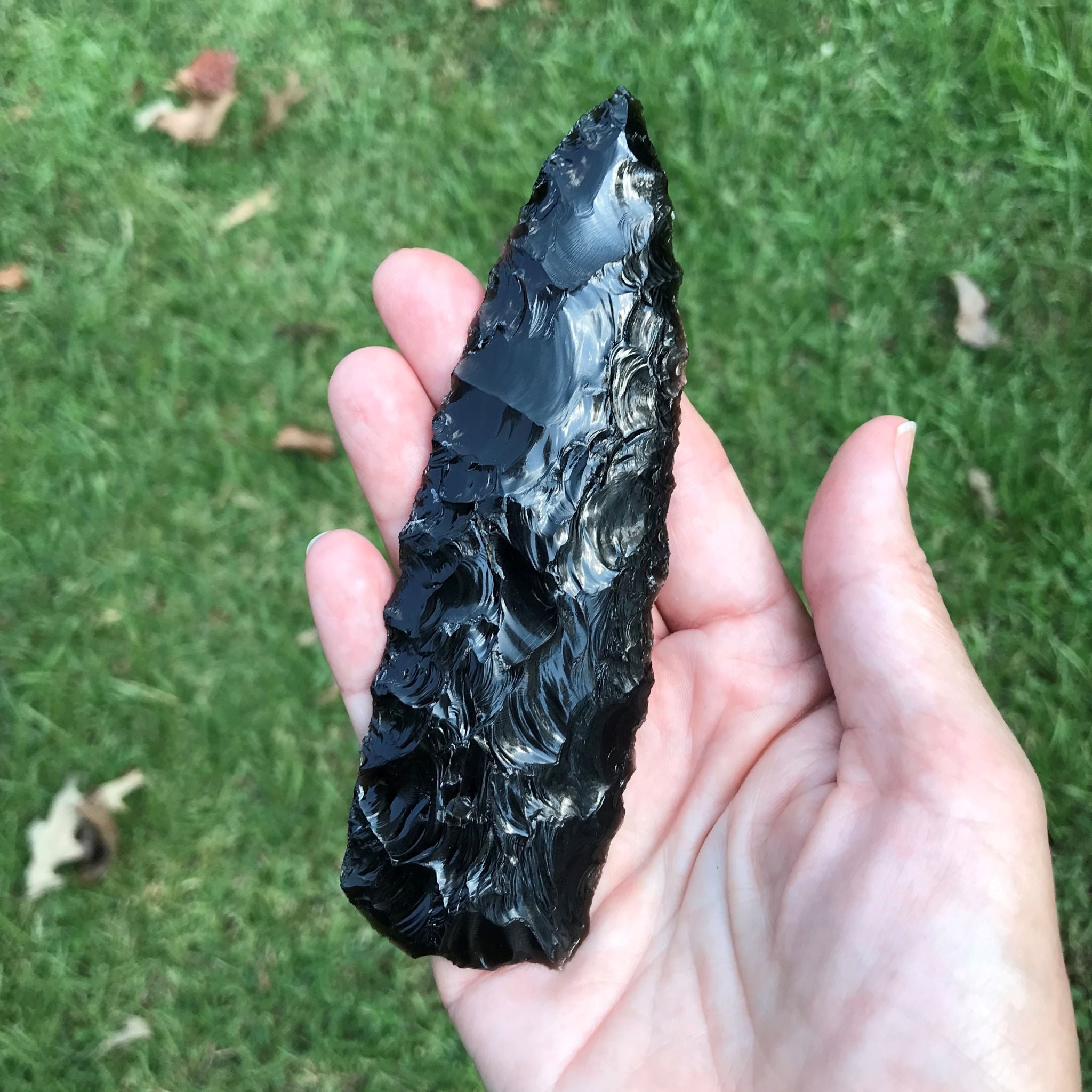 Black obsidian knapped blade with deep flaking in hand