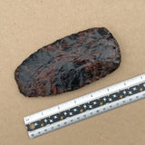 Large mahogany tomahawk head next to a ruler on a brown background