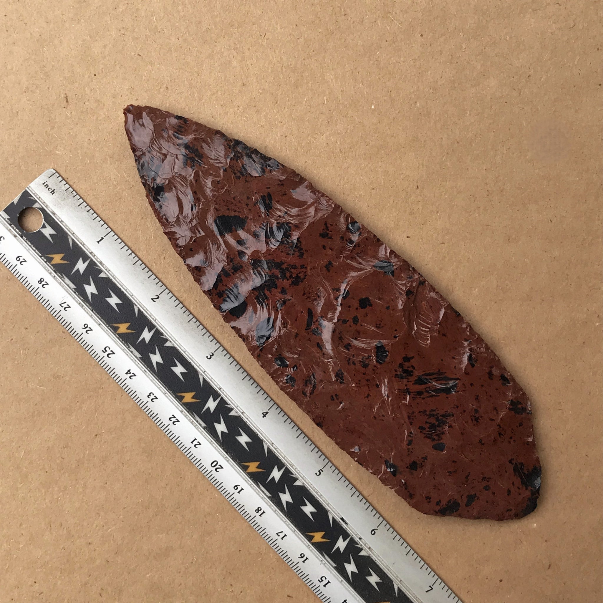 Mahogany lance blade, spearhead on a brown background with a ruler for scale.