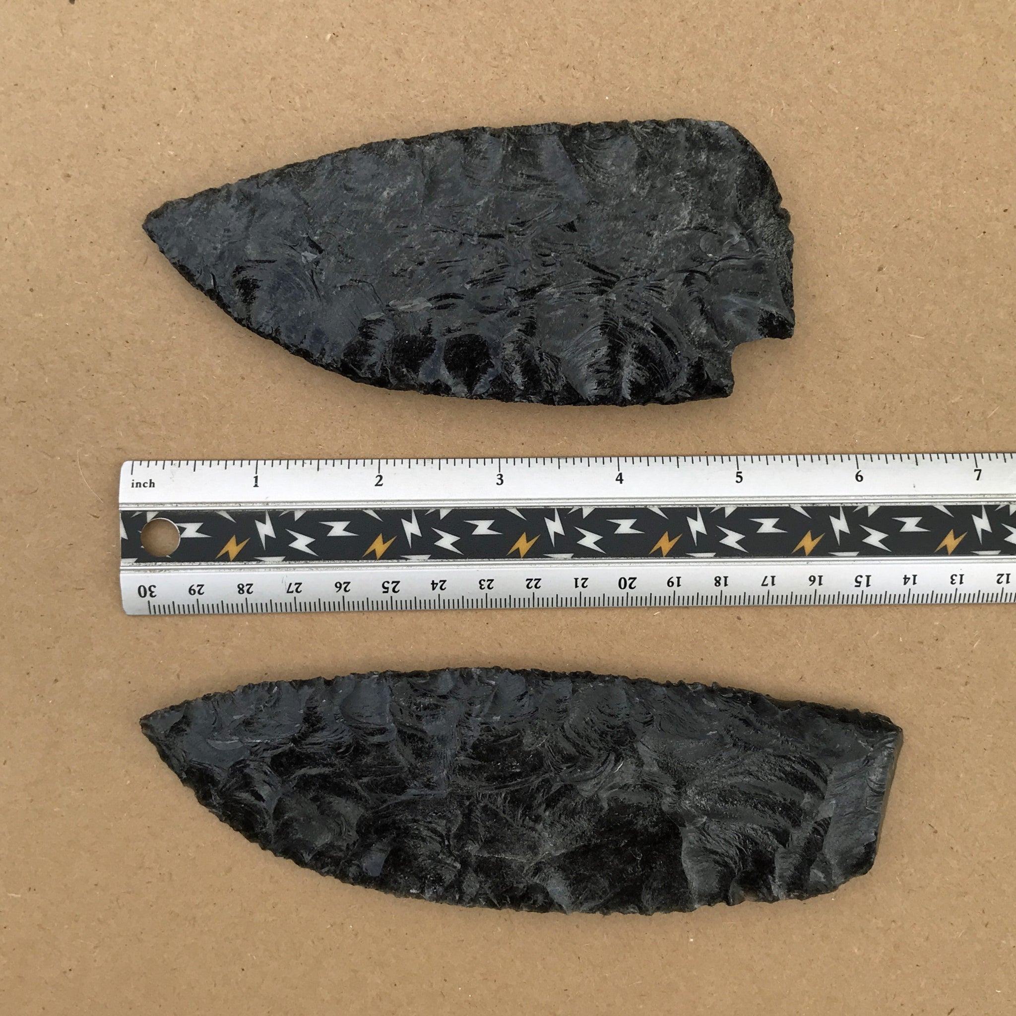 2 black sheen obsidian blades with ruler for scale, reverse side