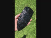 large black obsidian axe head rotated in hand