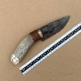 Knife with antler handle next to a ruler on a brown background