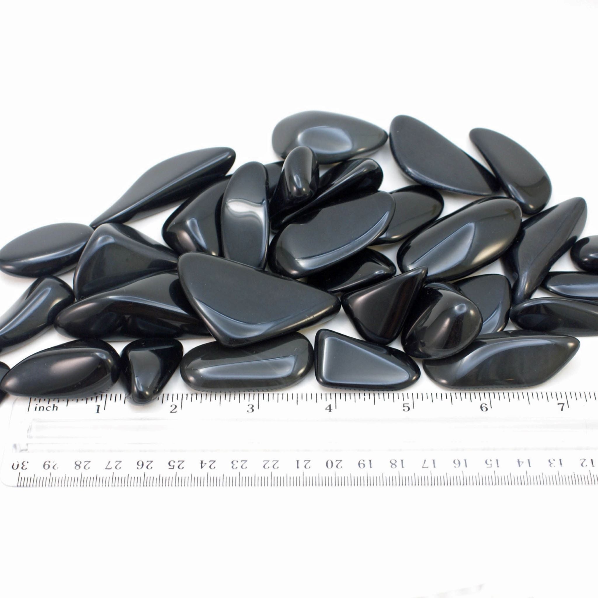 close-up of black obsidian tumbled stones with ruler