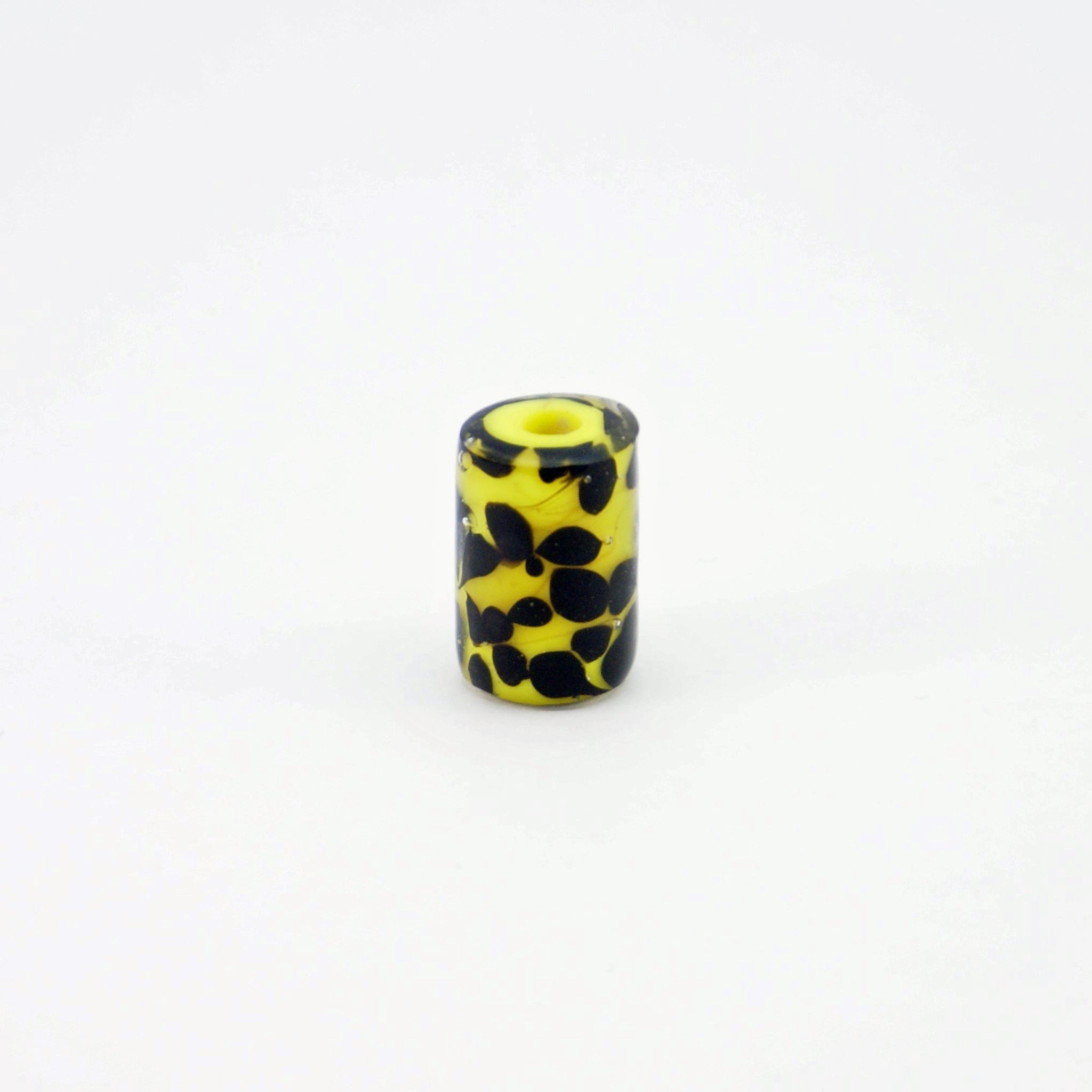 Yellow glass bead with black tadpole-like dots standing on end