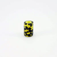 Yellow glass bead with black tadpole-like dots standing on end